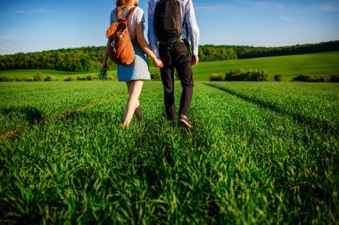 Genç çift greenfield ile geziniyor. Kadın ve erkek birbirlerini tarafından el ele tutuşarak.