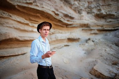 Bir akıllı telefon ekranına bir kum ocağı özgeçmişlerine bakarak çekici bir adam.