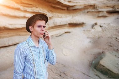 Çekici bir adam bir kum ocağı ortasında duran ve bir akıllı telefon üzerinden arama yapma.