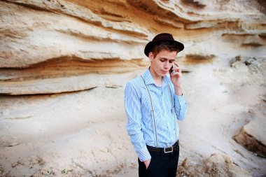 Çekici bir adam bir kum ocağı ortasında duran ve bir akıllı telefon üzerinden arama yapma.