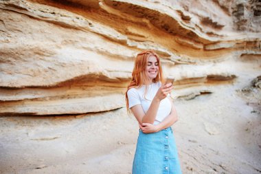 Gülümseyen ve bir akıllı telefon ekranına bir kum ocağı özgeçmişlerine bakarak güzel kadın.