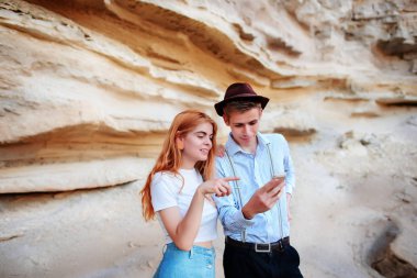 Çekici bir adam ve güzel kadın bir akıllı telefon ekranında bir kum ocağı arka plan üzerinde arıyoruz.