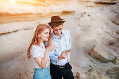 Çekici bir adam ve güzel kadın bir akıllı telefon ekranında bir kum ocağı arka plan üzerinde arıyoruz.