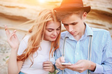 Çekici bir adam ve güzel kadın bir akıllı telefon ekranında bir kum ocağı arka plan üzerinde arıyoruz.