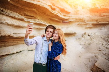 Çekici bir adam güzel bir kadın ile sarılma ve gülümseyerek. Onlar kum ocağı arka plan üzerinde selfie yapıyoruz.