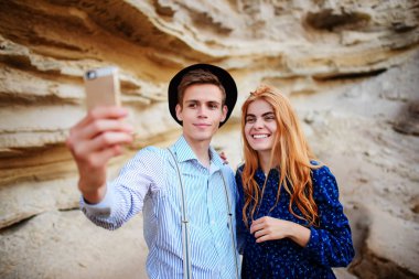 Çekici bir adam güzel bir kadın ile sarılma ve gülümseyerek. Onlar kum ocağı arka plan üzerinde selfie yapıyoruz.