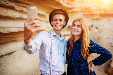 Çekici bir adam güzel bir kadın ile sarılma ve gülümseyerek. Onlar kum ocağı arka plan üzerinde selfie yapıyoruz.