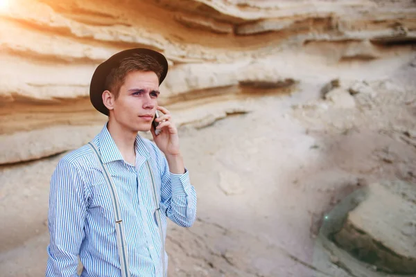 Çekici bir adam bir kum ocağı ortasında duran ve bir akıllı telefon üzerinden arama yapma.