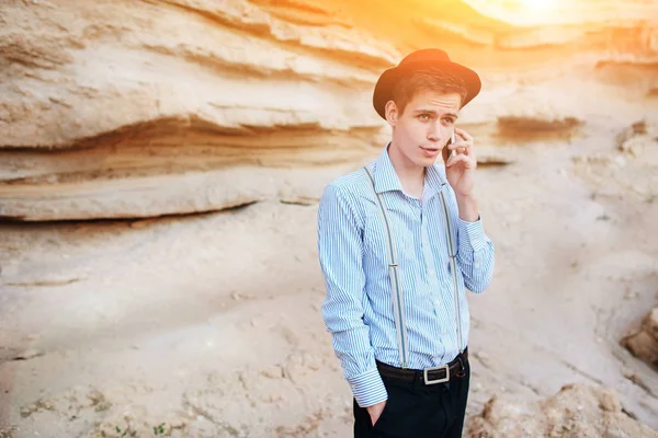 Çekici bir adam bir kum ocağı ortasında duran ve bir akıllı telefon üzerinden arama yapma.