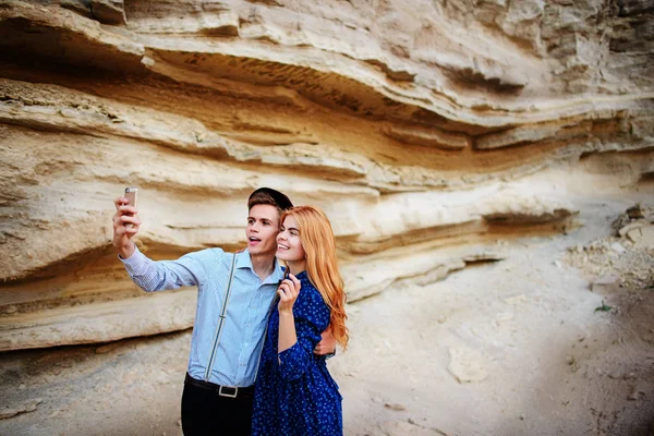 Çekici bir adam güzel bir kadın ile sarılma ve gülümseyerek. Onlar kum ocağı arka plan üzerinde selfie yapıyoruz.