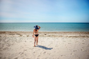 mavi şapkalı, güzel kız sahilde yürüyüş.