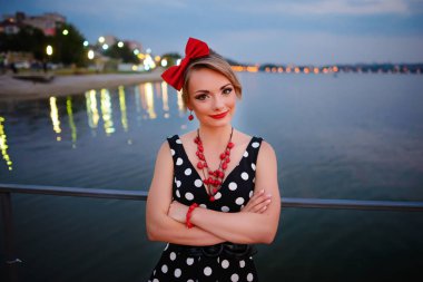 Akşam bir güzel genç kadın giyinmiş stand-pier üzerine.