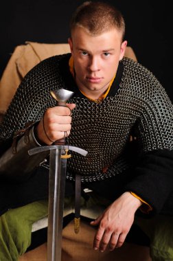 Bir asker mektupları zincirinin onun elinde bir kılıç tutan oturuyor.