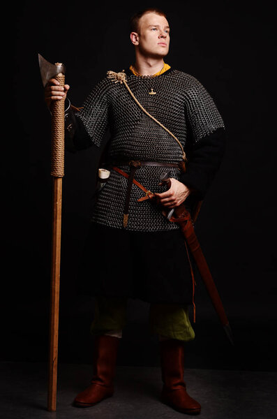 Male medieval warrior in armour and chain mail, viking with battle ax in hands .