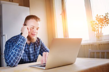 Genç işadamı onun laptop ile yaptığı telefon ederken onun masasında derin konsantrasyon yalan bir grafik bakarak.