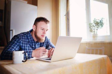 Ofiste cama tabloda, dizüstü bilgisayar ve akıllı telefon kullanan adam.