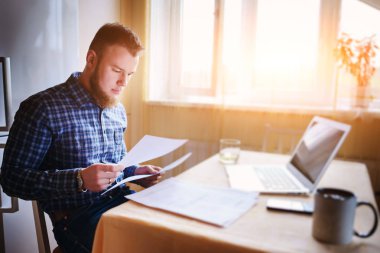 Evde biraz evrak işi yapan yakışıklı erkek.