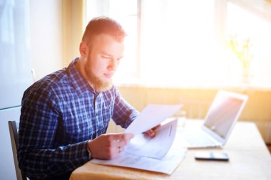 Evde biraz evrak işi yapan yakışıklı erkek.