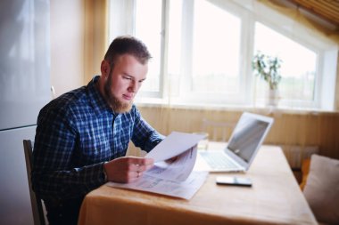 Evde biraz evrak işi yapan yakışıklı erkek.
