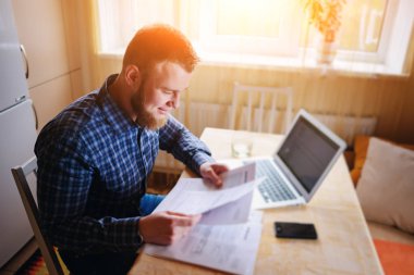 Evde biraz evrak işi yapan yakışıklı erkek.