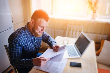 Evde biraz evrak işi yapan yakışıklı erkek.