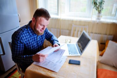 Evde biraz evrak işi yapan yakışıklı erkek.