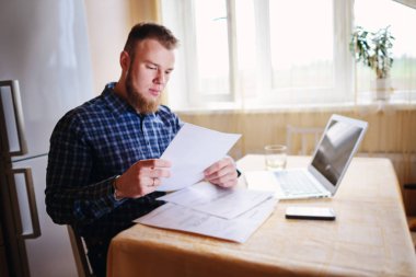 Evde iş adamı, evrak ve faturaları kontrol ile bir dizüstü bilgisayar, çalışıyor.