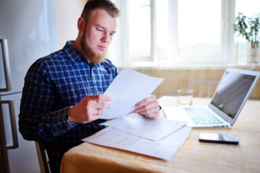 Evde iş adamı, evrak ve faturaları kontrol ile bir dizüstü bilgisayar, çalışıyor.