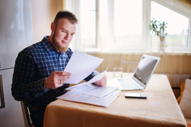 Evde iş adamı, evrak ve faturaları kontrol ile bir dizüstü bilgisayar, çalışıyor.