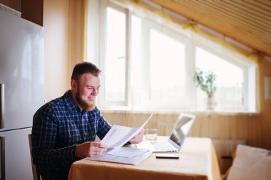 Evde iş adamı, evrak ve faturaları kontrol ile bir dizüstü bilgisayar, çalışıyor.