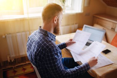 Evde iş adamı, evrak ve faturaları kontrol ile bir dizüstü bilgisayar, çalışıyor.