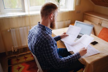 Evde iş adamı, evrak ve faturaları kontrol ile bir dizüstü bilgisayar, çalışıyor.