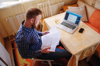 Evde iş adamı, evrak ve faturaları kontrol ile bir dizüstü bilgisayar, çalışıyor.