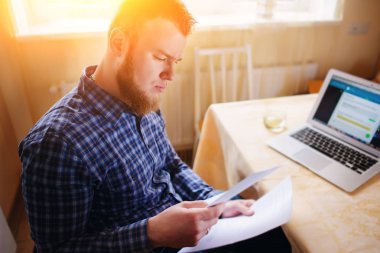 Evde iş adamı, evrak ve faturaları kontrol ile bir dizüstü bilgisayar, çalışıyor.