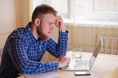 Evde dizüstü bilgisayarda çalışan genç adam..