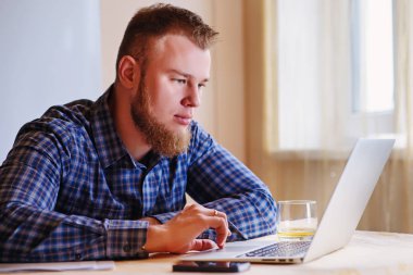 Evde dizüstü bilgisayarda çalışan genç adam..