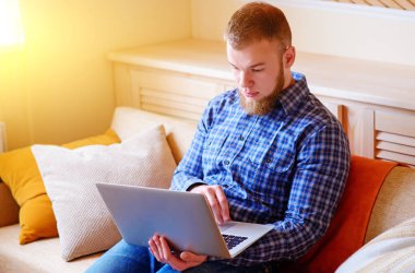 dizüstü bilgisayarınızda evde absorbe çalışan genç adam.