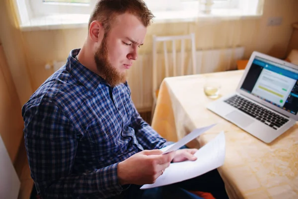 Evde iş adamı, evrak ve faturaları kontrol ile bir dizüstü bilgisayar, çalışıyor.
