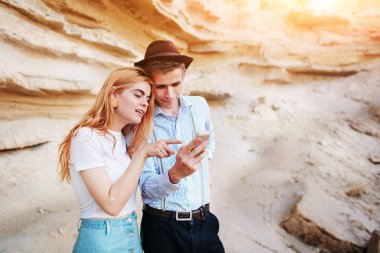 Çekici bir adam ve güzel kadın bir akıllı telefon ekranında bir kum ocağı arka plan üzerinde arıyoruz.