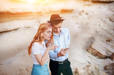 Çekici bir adam ve güzel kadın bir akıllı telefon ekranında bir kum ocağı arka plan üzerinde arıyoruz.