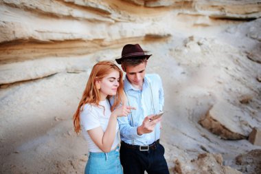 Çekici bir adam ve güzel kadın bir akıllı telefon ekranında bir kum ocağı arka plan üzerinde arıyoruz.