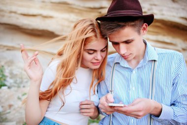 Çekici bir adam ve güzel kadın bir akıllı telefon ekranında bir kum ocağı arka plan üzerinde arıyoruz.