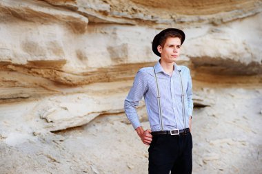 Şık çekici adam bir kum ocağı ortasında duruyor ve kameraya poz veriyor.