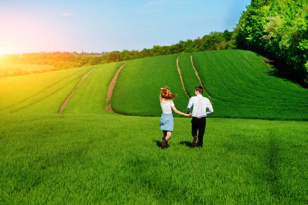 Mutlu aşıklar çayır yeşil çim ve arkasından mavi gökyüzü ile çalışan.