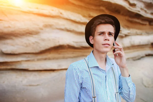 Çekici bir adam bir kum ocağı ortasında duran ve bir akıllı telefon üzerinden arama yapma.