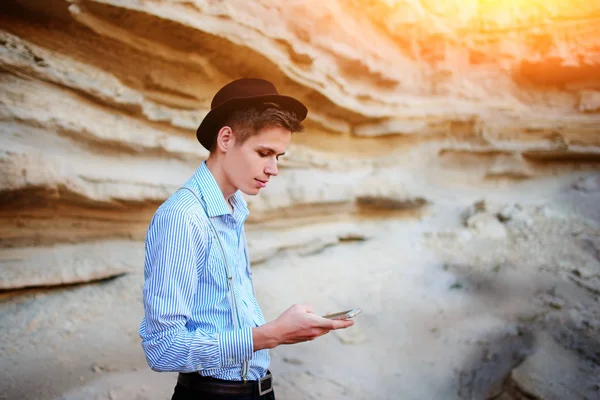 Bir akıllı telefon ekranına bir kum ocağı özgeçmişlerine bakarak çekici bir adam.