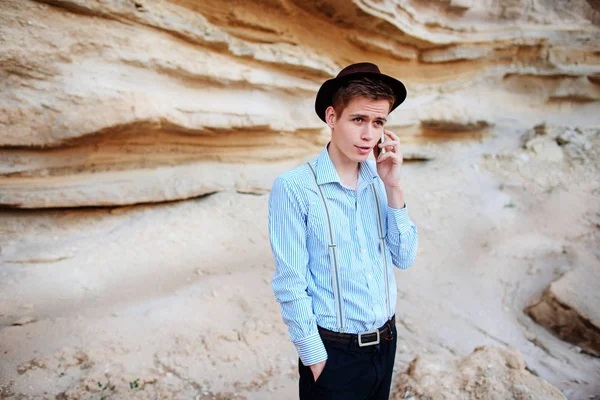 Çekici bir adam bir kum ocağı ortasında duran ve bir akıllı telefon üzerinden arama yapma.