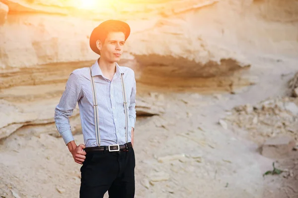 Şık çekici adam bir kum ocağı ortasında duruyor ve kameraya poz veriyor.