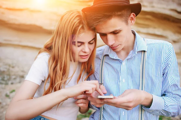 Çekici bir adam ve güzel kadın bir akıllı telefon ekranında bir kum ocağı arka plan üzerinde arıyoruz.