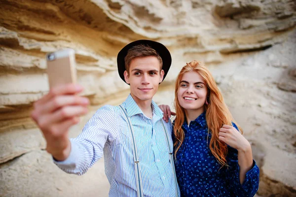 Çekici bir adam güzel bir kadın ile sarılma ve gülümseyerek. Onlar kum ocağı arka plan üzerinde selfie yapıyoruz.